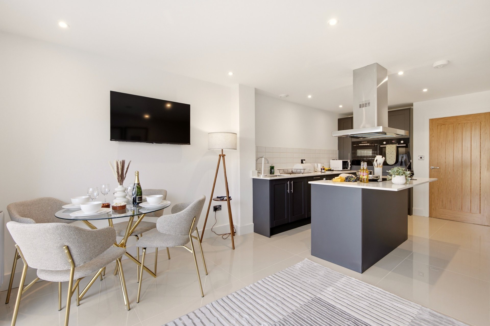 Modern open-plan kitchen and dining area with island, dining table, and wall-mounted television