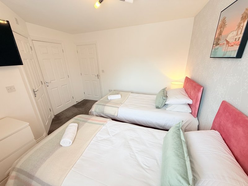 Twin bedroom with two single beds, red headboards, white bedding and green throws