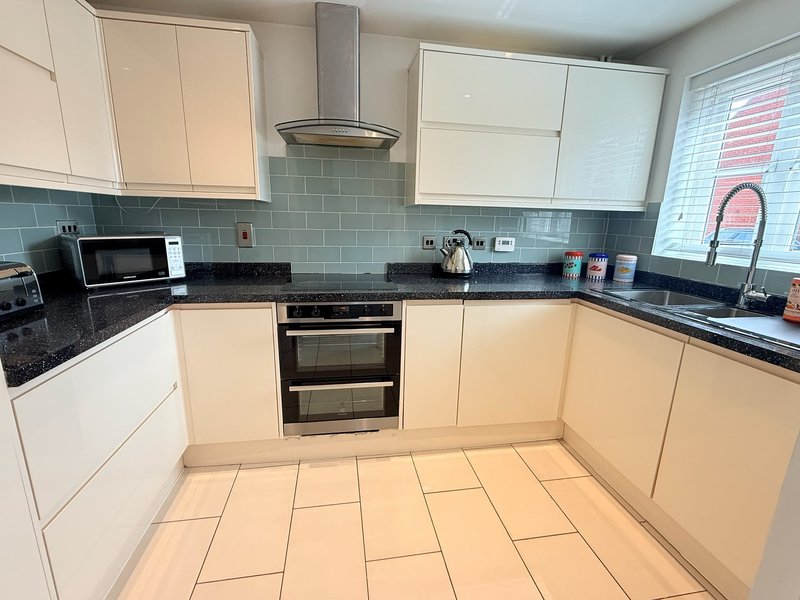 Modern kitchen with cream cabinets, black countertop, tiled backsplash and flooring