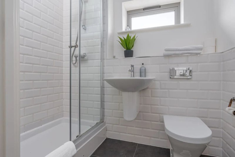 Modern bathroom with white subway tiles, shower enclosure, pedestal sink and toilet