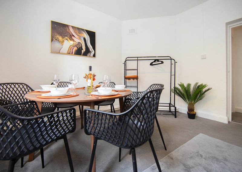 Modern dining area with wooden table, black patterned chairs, and wall art