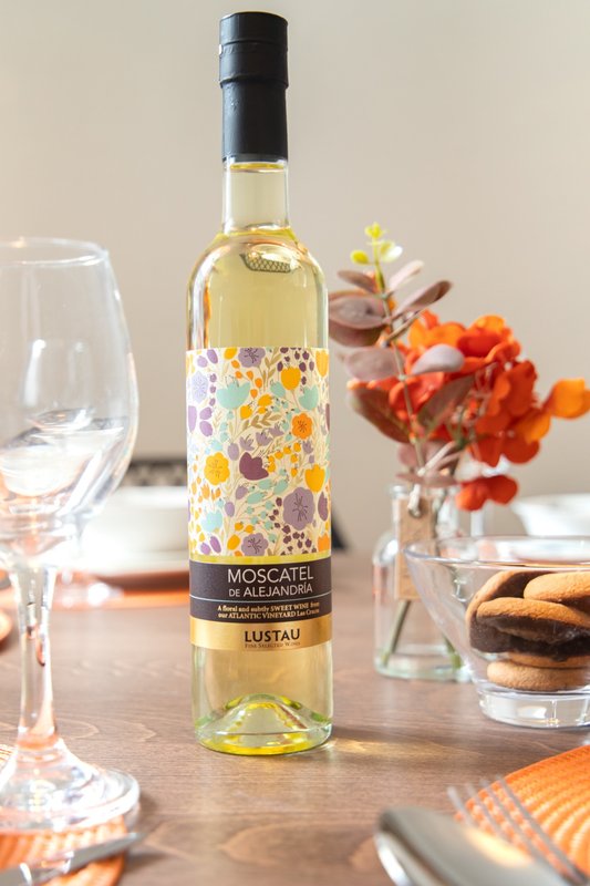 Dining table with wine bottle, glasses, flowers in vase, and place settings
