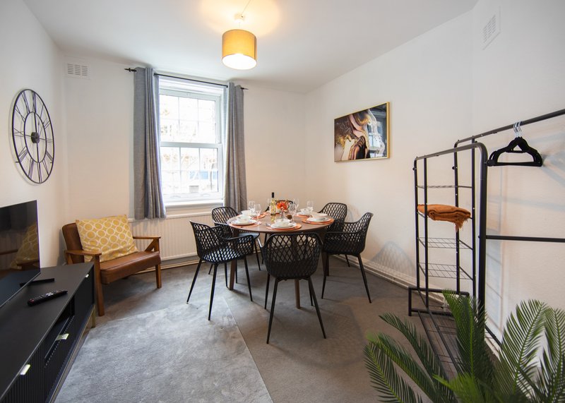 Bright dining area with round table, modern chairs, yellow armchair, and potted plants