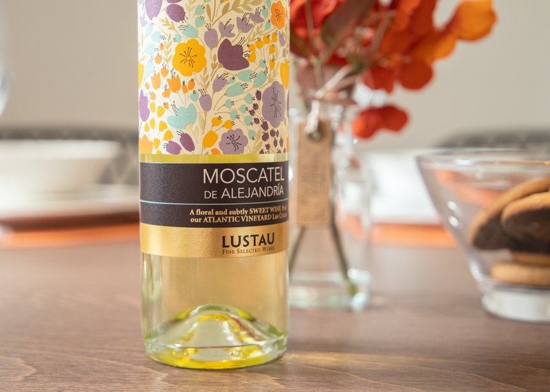Bottle of Moscatel wine on dining table with flowers and glassware