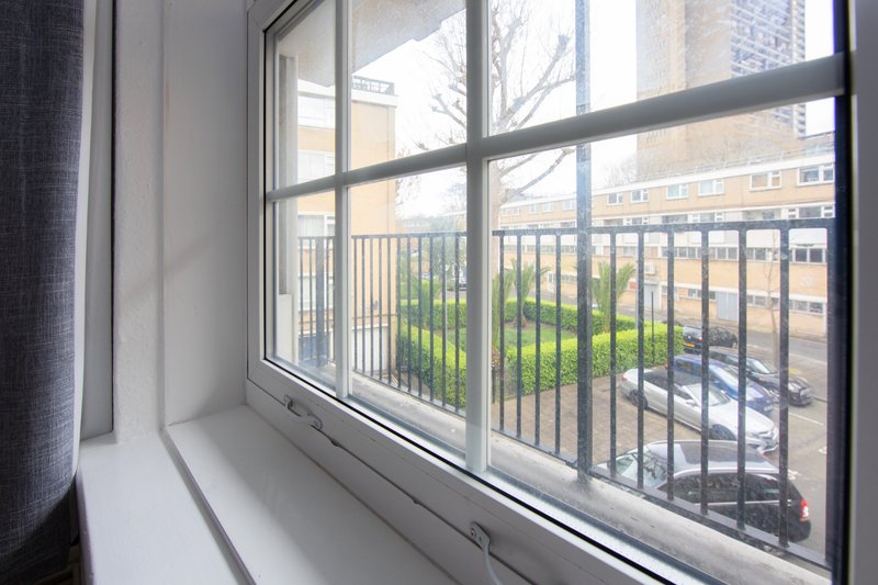Window view of urban courtyard with balcony railing and neighboring buildings