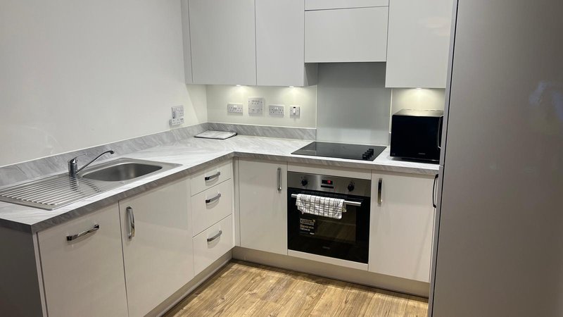 Modern white kitchen with built-in oven, hob, sink and marble worktops