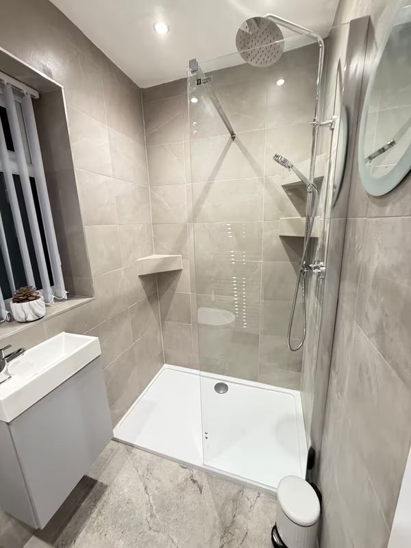 Modern bathroom with shower enclosure, white vanity sink, and tiled walls