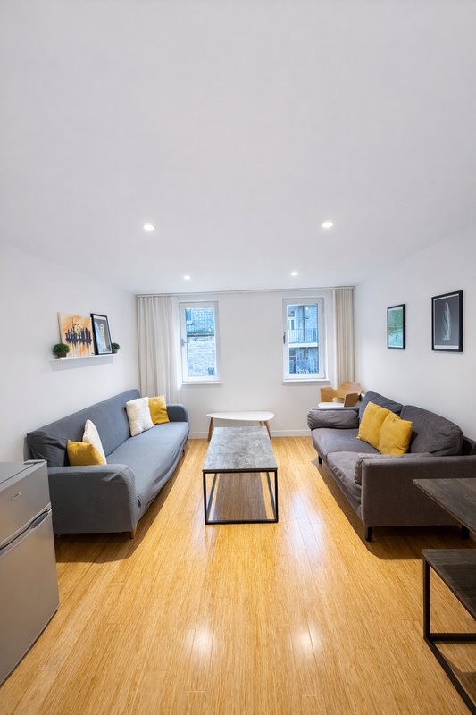 Modern living room with two gray sofas, wooden floor, coffee table, and large windows