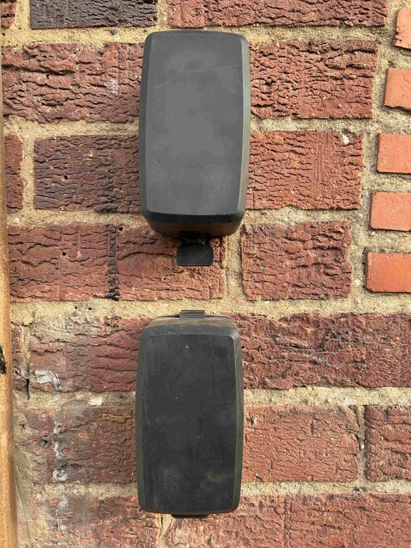 Two black wall-mounted downpipes on red brick exterior wall