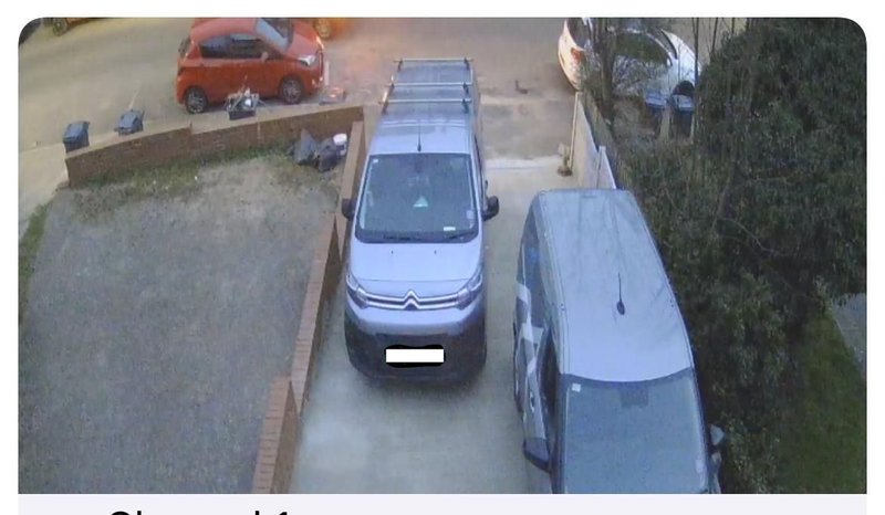 Aerial view of driveway with parked vehicles and residential street access