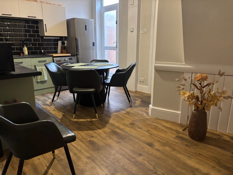 Open-plan kitchen and dining area with black dining table, modern chairs, and wooden flooring