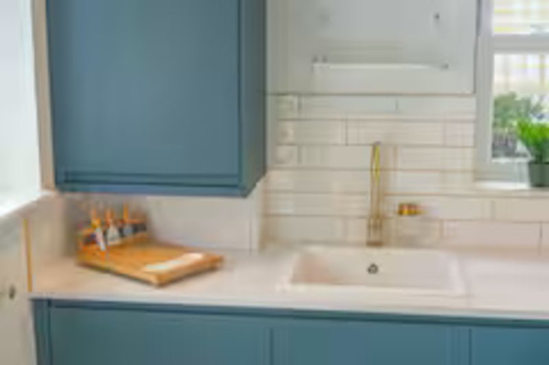 Modern bathroom with teal cabinetry, white subway tile backsplash, and brass fixtures
