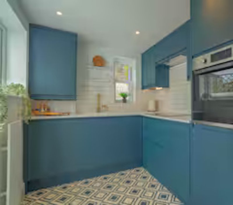 Modern kitchen with blue cabinetry, white subway tile backsplash, integrated appliances