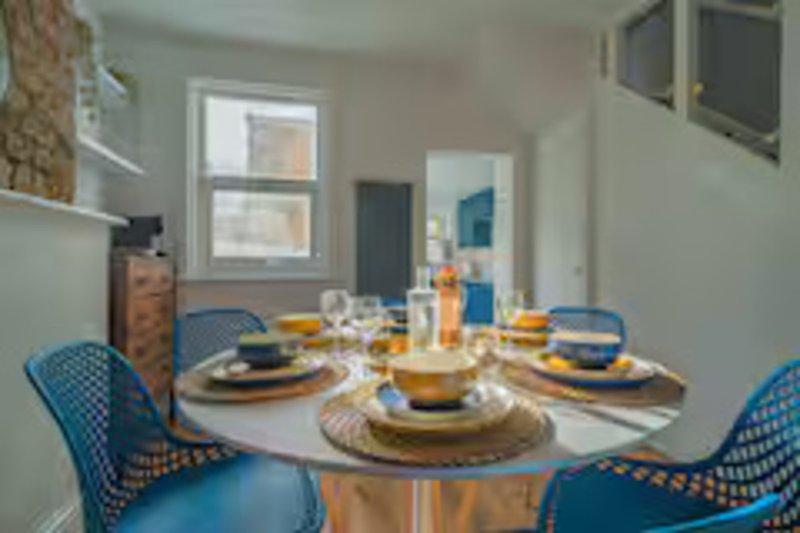 Dining area with round table, blue chairs, place settings and window views
