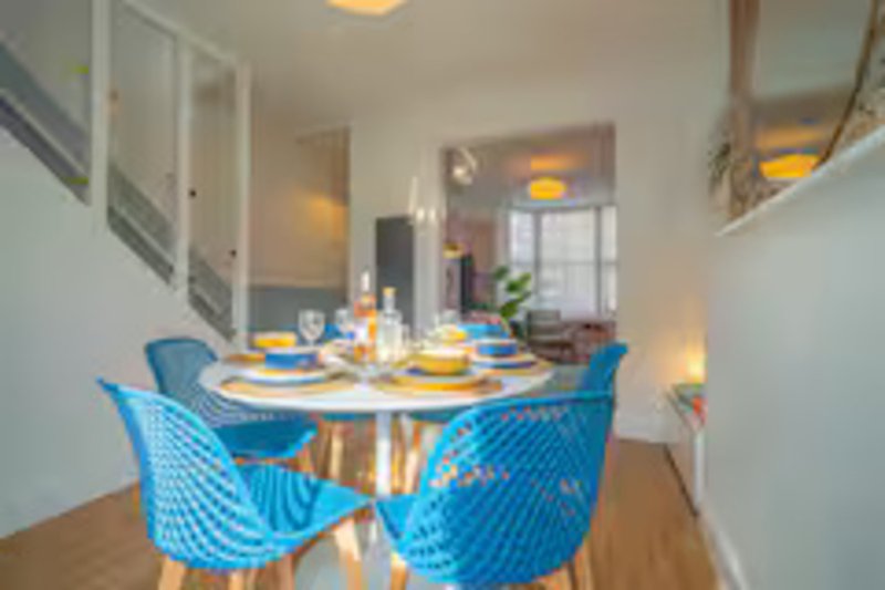 Modern dining area with round table, blue chairs, and place settings