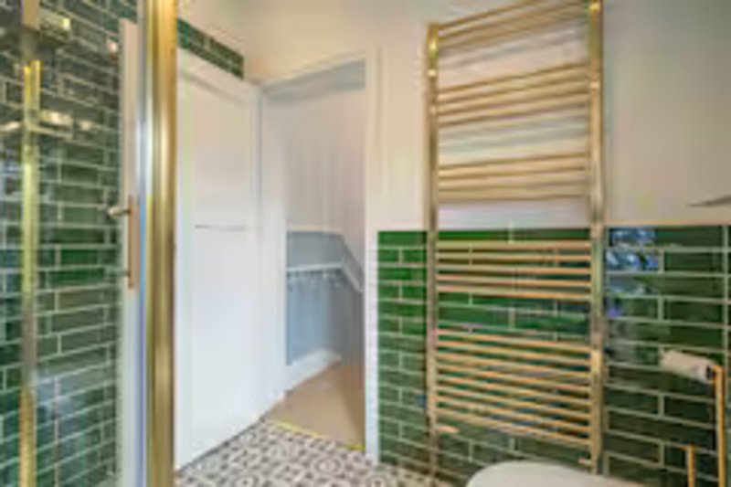 Modern bathroom with green tile walls, gold-framed heated towel rail and mirror