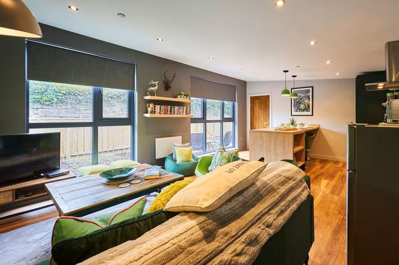 Open-plan living room with sofa, TV, dining area, wooden floors and garden views
