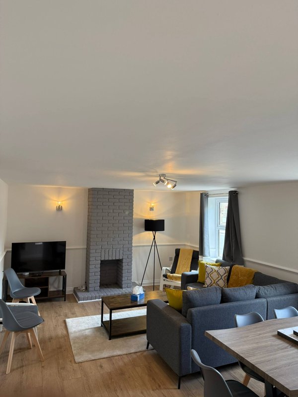 Spacious living room with fireplace, sofas, TV, wooden floor and dining area