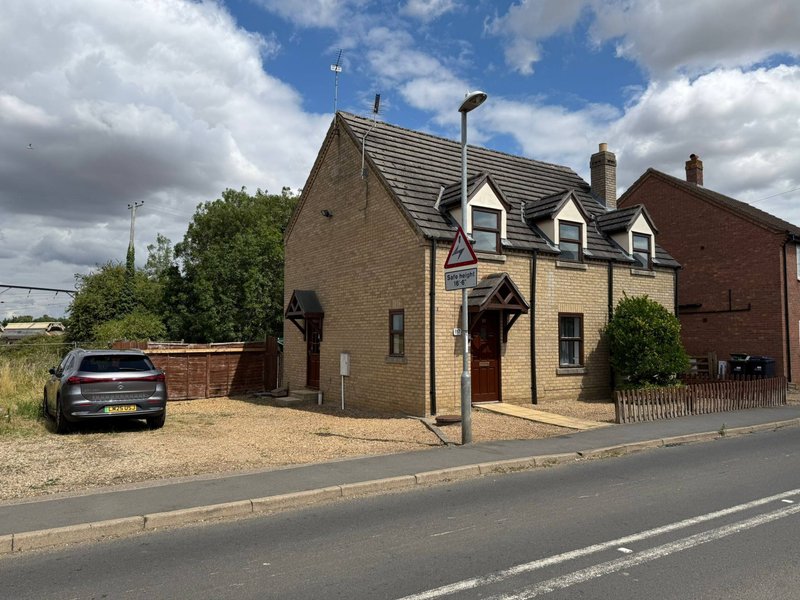 Stone cottage with dormer windows, driveway, parked car and front garden
