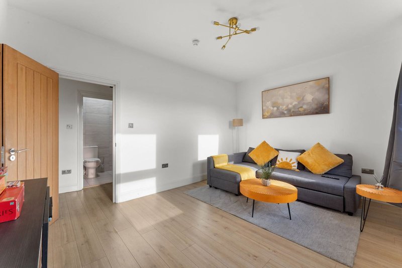 Modern living room with dark sofa, yellow cushions, wooden flooring and wall art