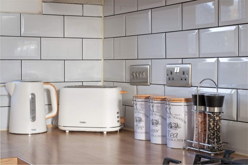 Kitchen countertop with white kettle, toaster, storage jars and white subway tile backsplash