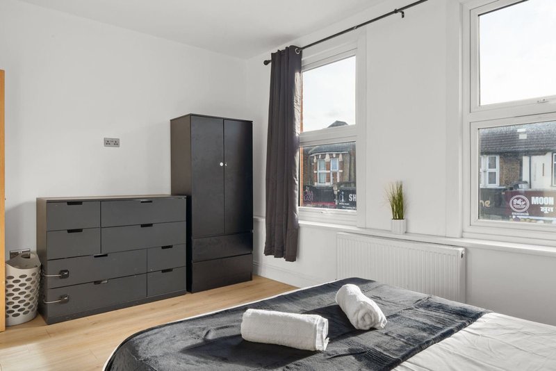 Bedroom with double bed, dark wooden furniture, large windows overlooking street