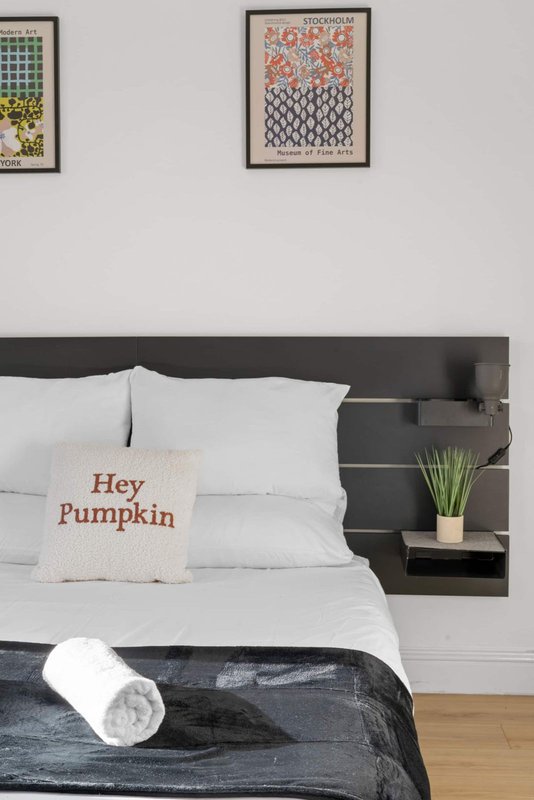 Bedroom with double bed, black headboard, decorative pillow, and framed wall art