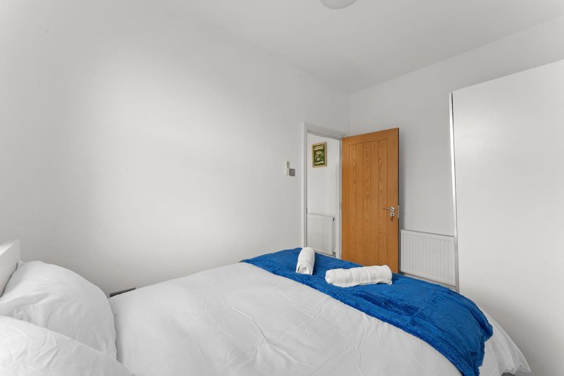 Simple bedroom with double bed, blue throw, white pillows and wooden door