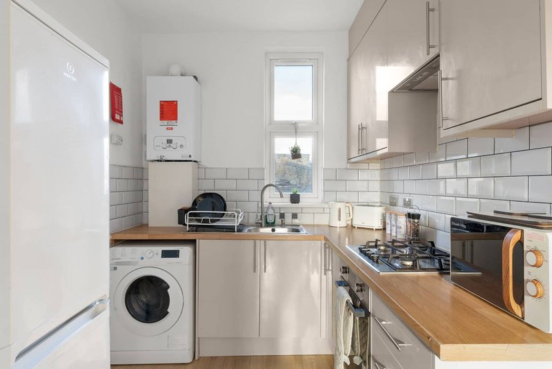 Modern kitchen with white cabinetry, wooden countertops, gas hob, washing machine, and subway tile splashback