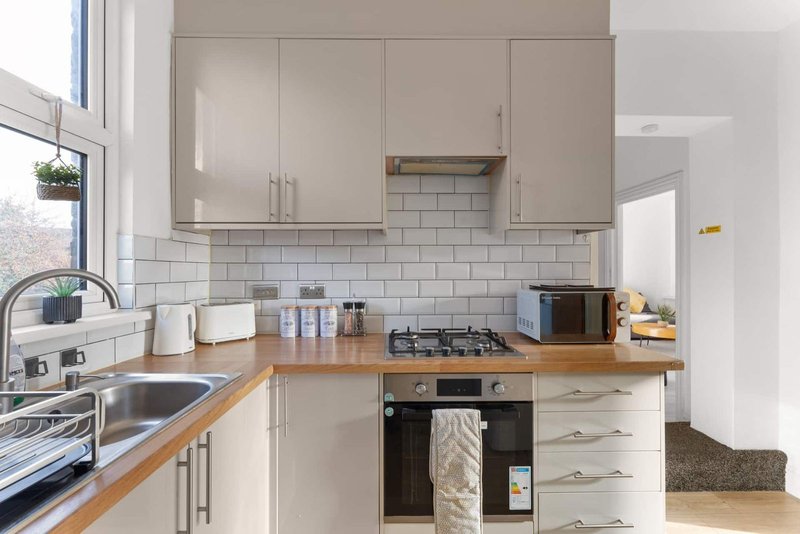 Modern kitchen with cream cabinets, wooden countertop, gas hob and white subway tile backsplash