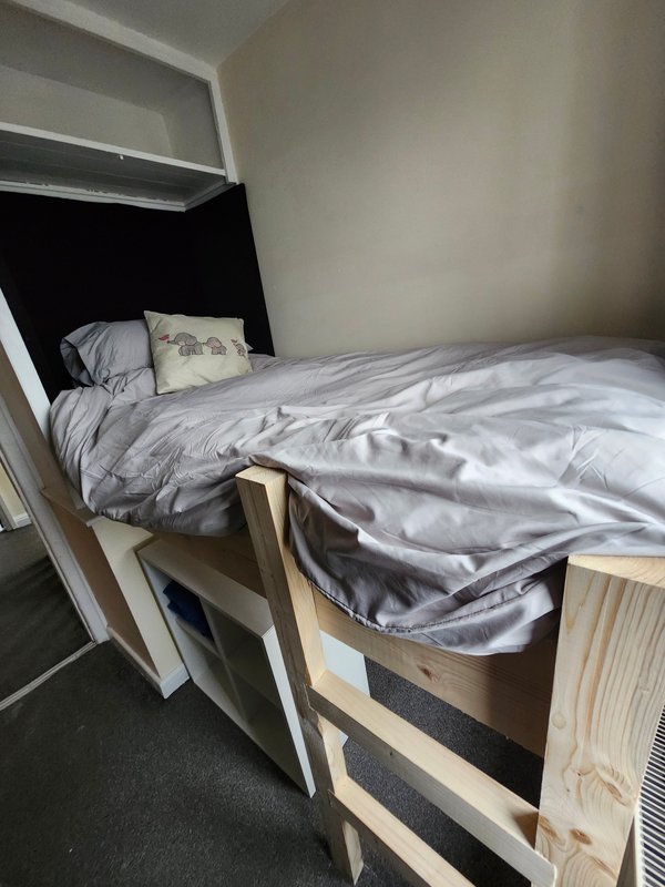 Compact bedroom with built-in bunk bed, grey bedding, and wooden frame