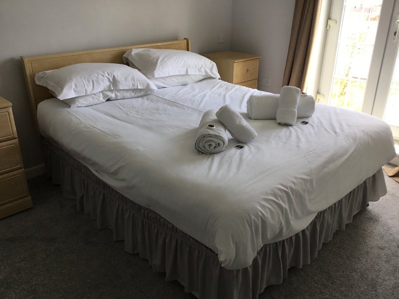 Bright bedroom with double bed, white bedding, wooden headboard and bedside tables