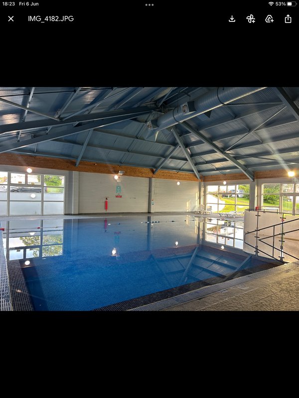 Indoor swimming pool with blue water, metal railings, skylights and windows