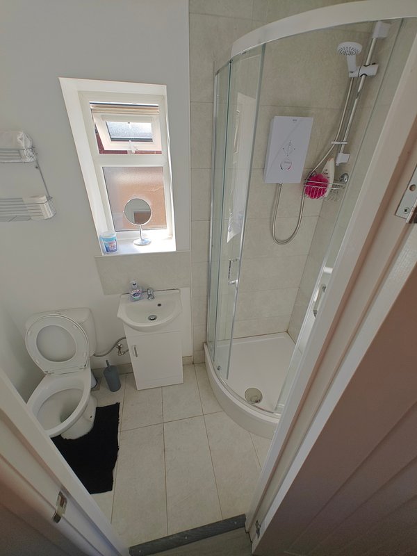 Small bathroom with toilet, sink, shower cubicle and skylight window