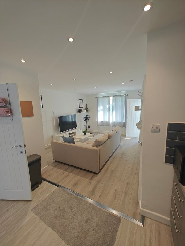 Modern living room with beige sofa, TV, wooden flooring and bright natural light