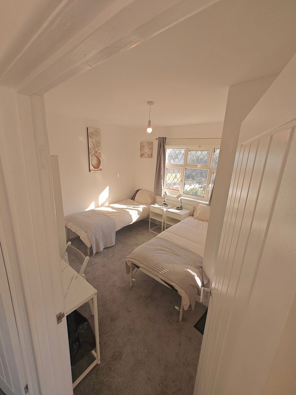 Bright bedroom with single bed, window, pendant light and neutral décor