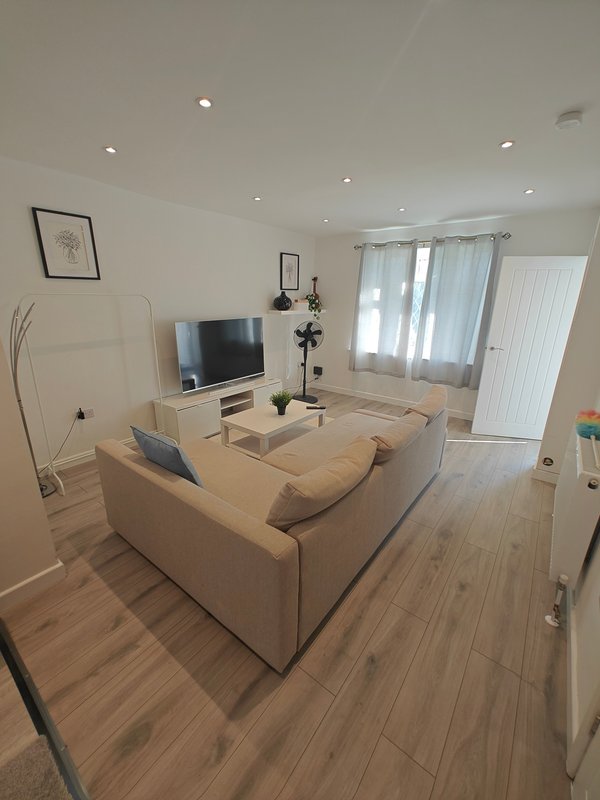 Bright living room with beige sofa, wooden flooring, TV unit and garden doors