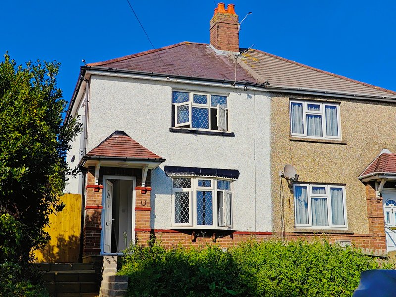 Semi-detached house with cream and yellow rendered exterior, red-brick details, pitched roof and front garden
