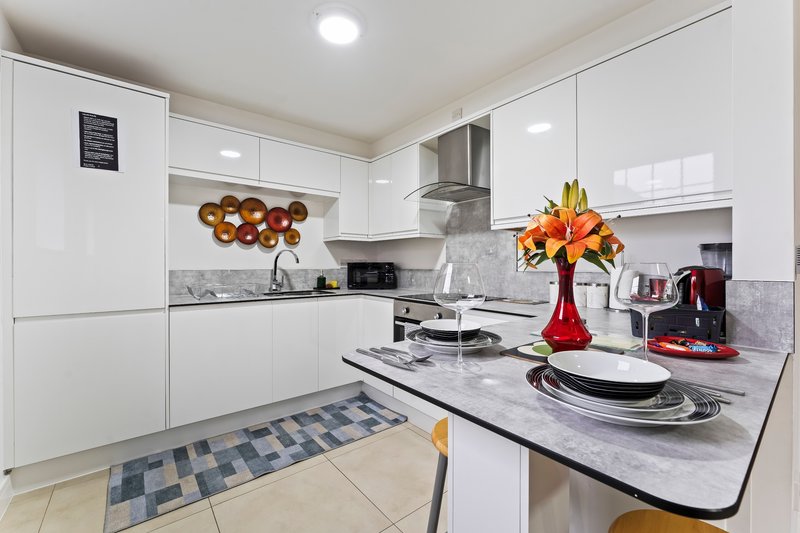 Modern white kitchen with island, marble countertops, flowers in vase, and dining setup