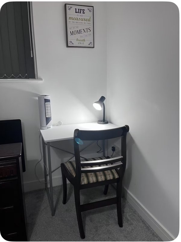 Small home office nook with white desk, black chair, desk lamp and wall decor