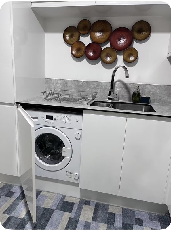 Compact utility room with washing machine, sink, and decorative wooden bowls on wall