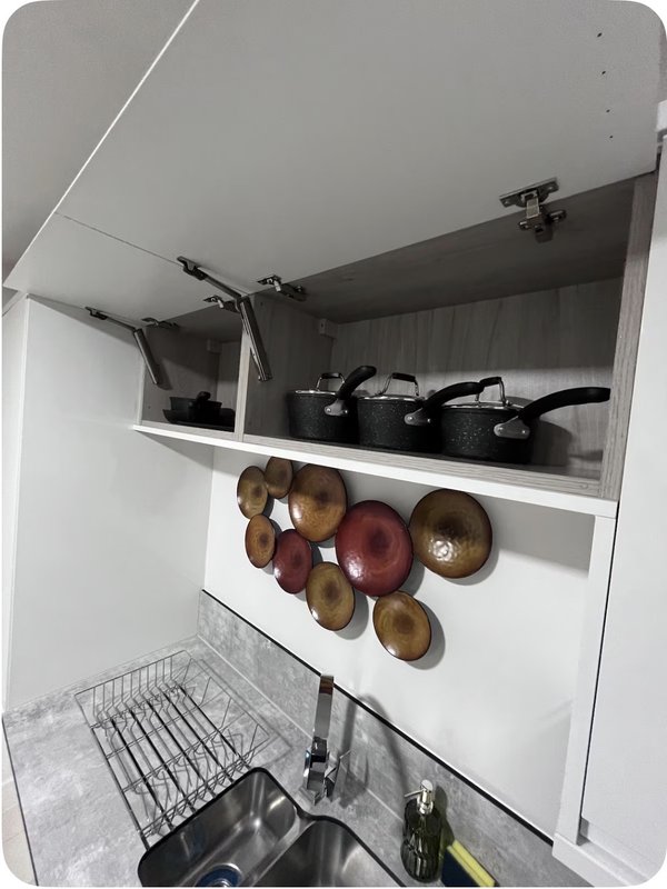 Kitchen cupboard interior with pans, wooden bowls, and wire dish rack