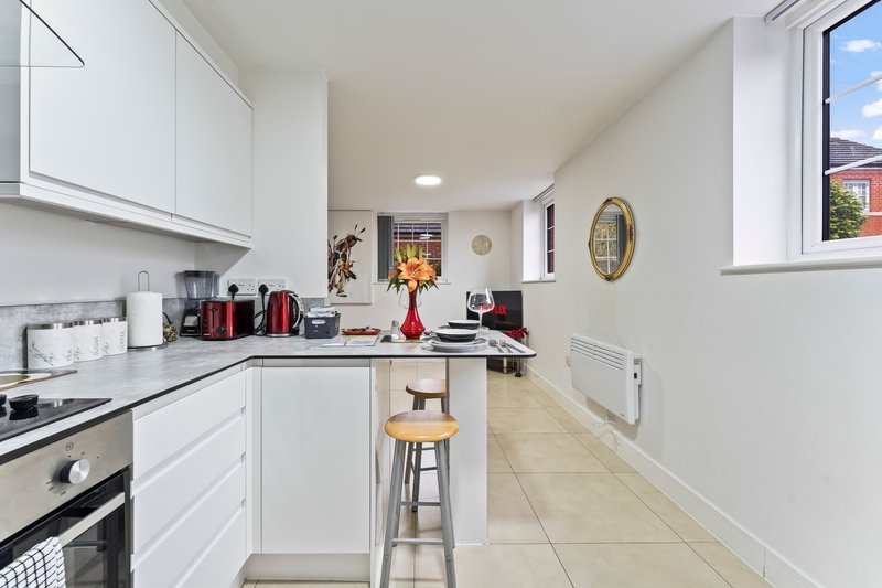 Modern white kitchen with island, bar seating, appliances and decorative items