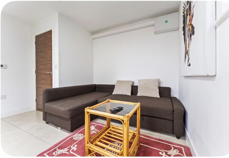 Modern living room with brown sectional sofa, wooden side table, and red patterned rug