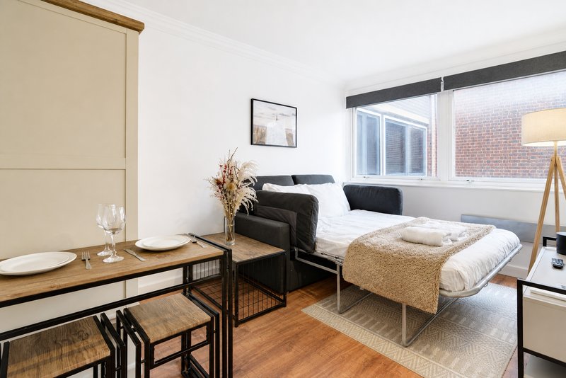 Modern studio apartment with bed, dining table, sofa and large window