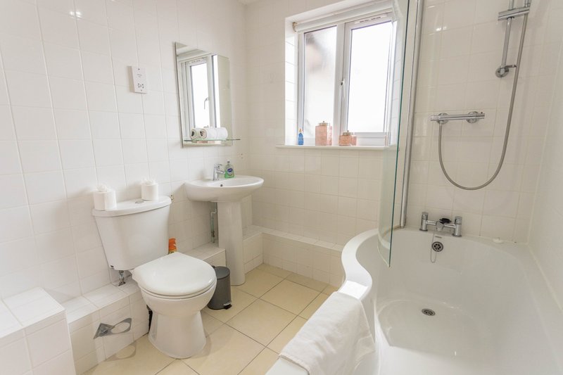 Clean modern bathroom with toilet, pedestal sink, bathtub and shower enclosure