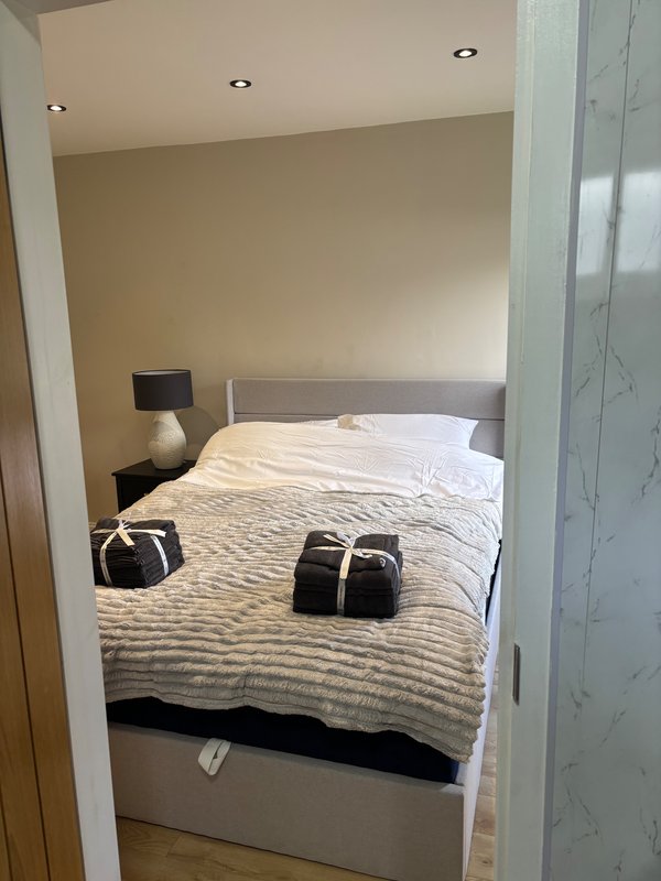 Bedroom with double bed, striped bedding, bedside lamp and recessed ceiling lights