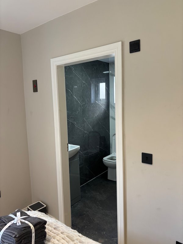 Bathroom doorway with black marble tiles, white frame, and cream walls