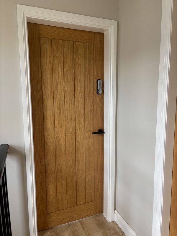 Wood-paneled interior door with white trim and electronic keypad lock