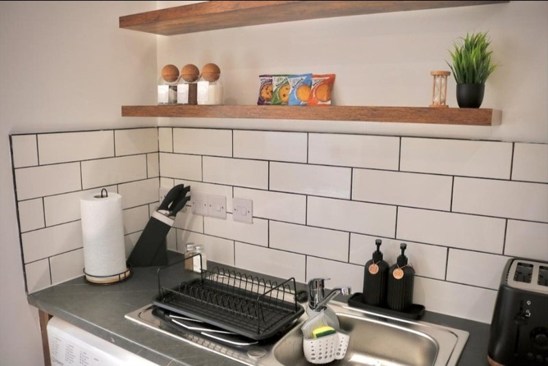 Modern kitchen with subway tile backsplash, wooden shelves, stainless steel sink and countertop styling